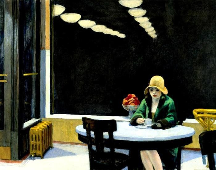 A young woman sitting by herself in a dark cafe